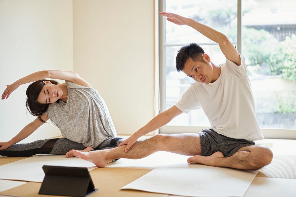 Asian Couple stretching exercises with digital tablet in the Japanese-style room at home.