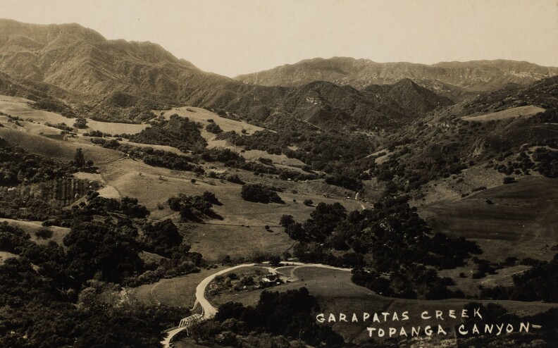 hills, trees, and a road with a bridge over a creek