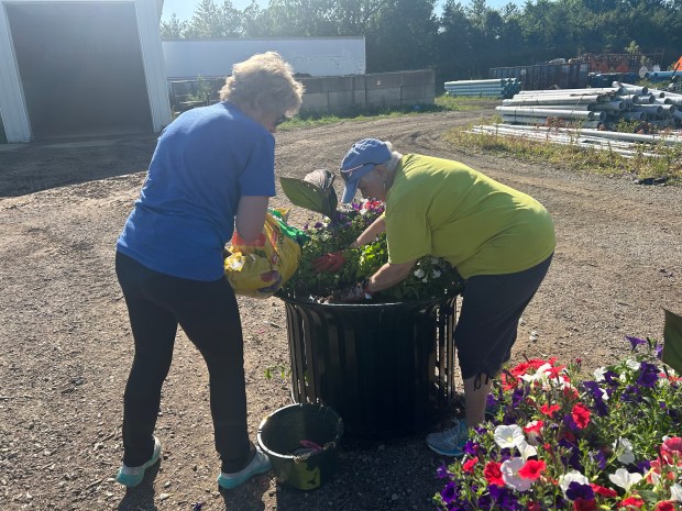 Volunteers Pam Mazzone (left) and Miriam Levin work together to plant a flower box at the Main Street Wellington Flower Planting event. (Larissa Beriswill - The Morning Journal)