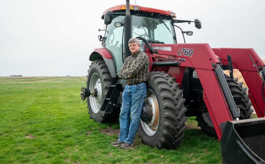 Bill Leigh stands for a portrait next to one of his tractors in front of the fields of corn and soybeans he farms in Marshall County, Illinois.