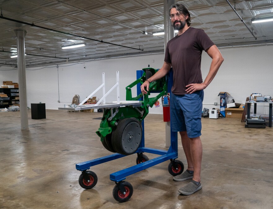 Impossible Sensing founder Pablo Sobron stands next to a single disk of a John Deere planter in his laboratory in St. Louis. The company sent him the equipment last year with the task of figuring out how to mount one of his soil sensors to the back of it.