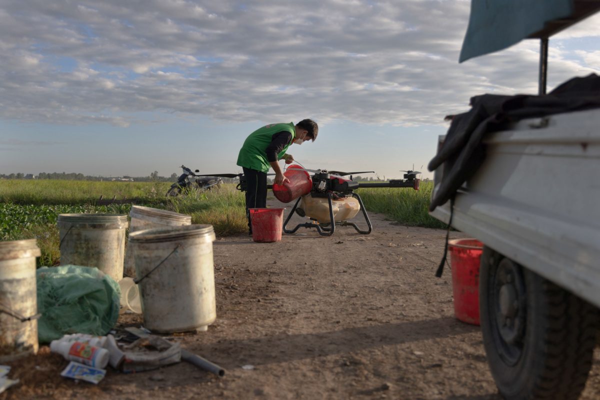 A young pilot fills a drone’s tank with fertilizer. 