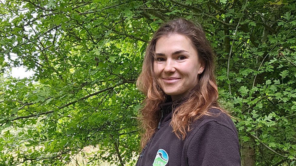 Sophie Arnold turned to look at the camera with a young and very leafy tree behind her